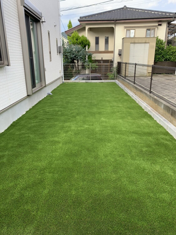 建物脇から続く細長い新築の庭を外壁の線に沿ってそろえた緑に｜秦野市の人工芝施工事例