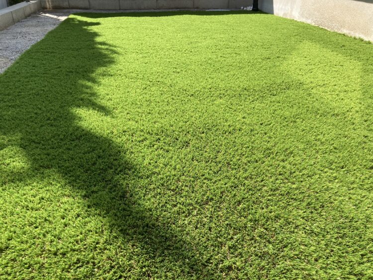 春日井市・建物脇の砂利通路が、鮮やかな緑の人工芝スペースに