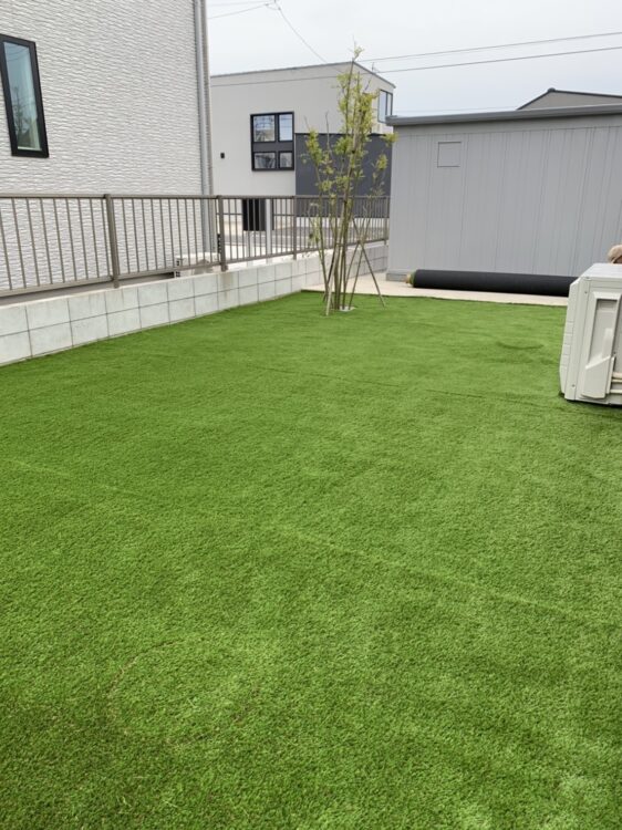 物置と室外機の並ぶ広い庭を草取りゼロの緑に｜神栖市の人工芝施工事例