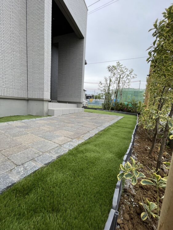 新築の玄関アプローチ脇を石畳の際まで敷き込んだ緑に｜千葉市の人工芝施工事例