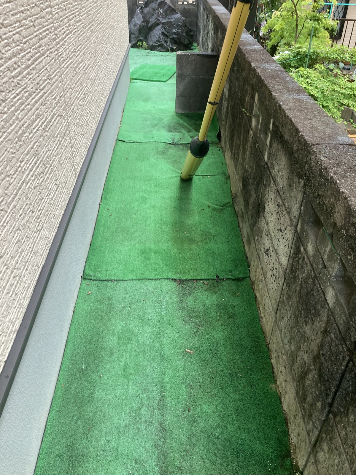 施工前：建物脇の通路に残る黒ずんだ既存の人工芝