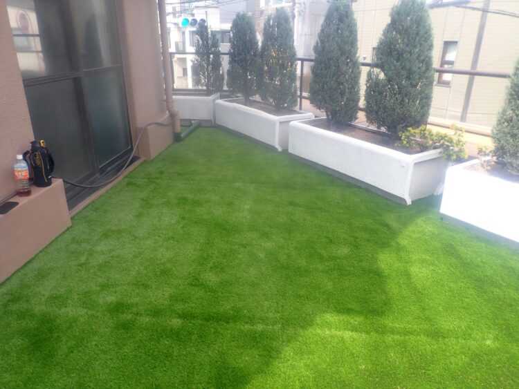 プランターの並ぶルーフバルコニーを鉢植えとつながる緑に｜人工芝施工事例
