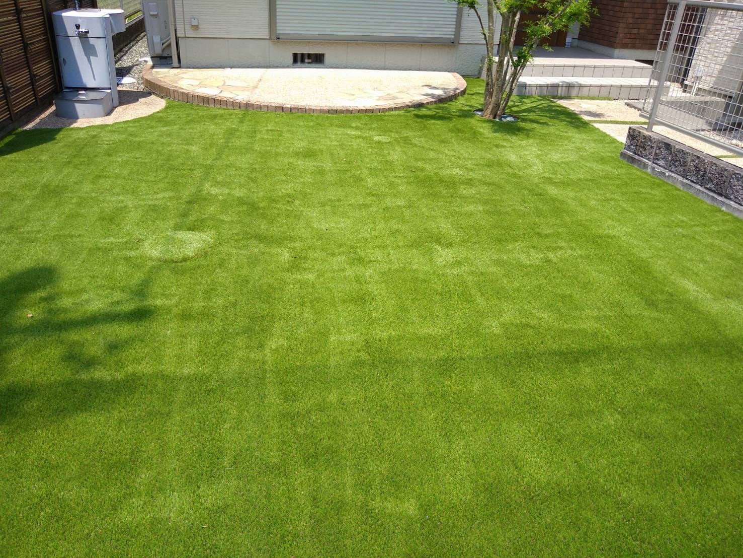施工後:石張りのテラスの際まで人工芝を敷いたお庭