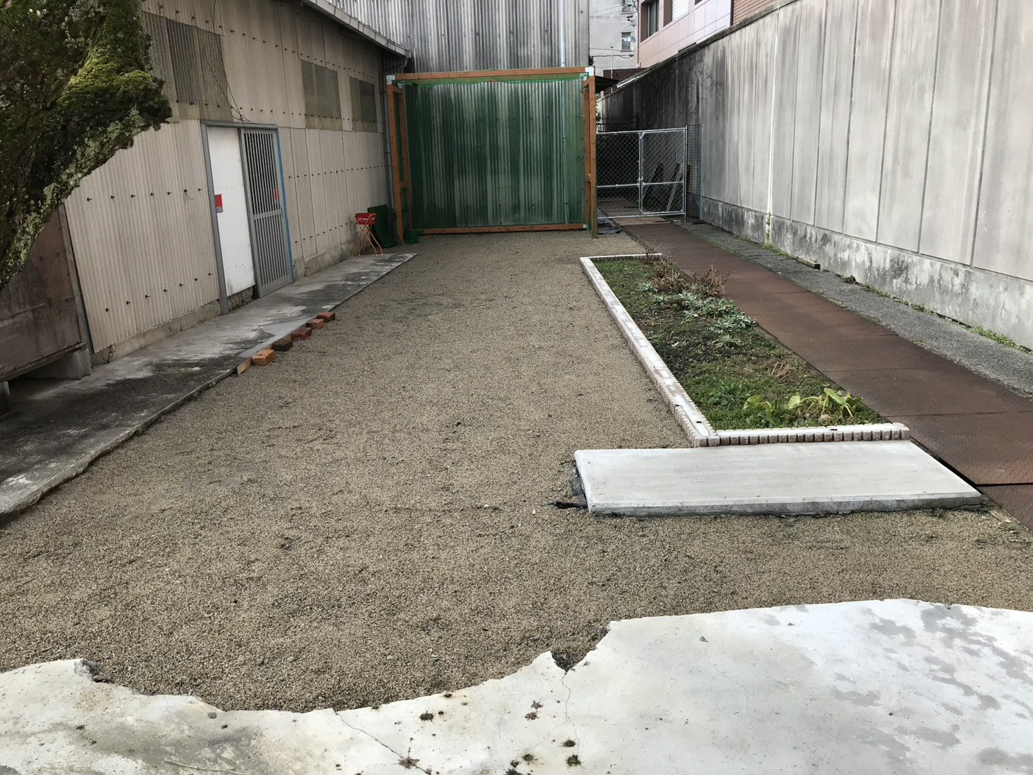 施工前の砂利敷きの工場裏庭、花壇脇から見た様子