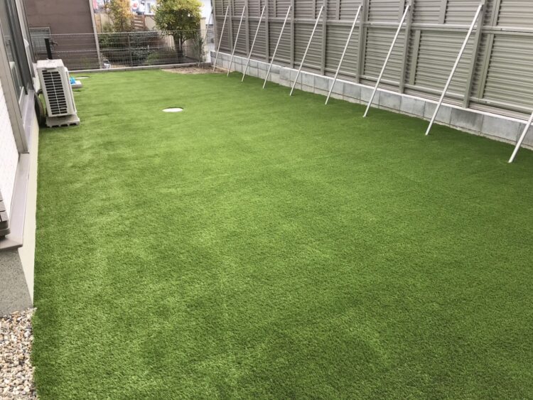 土がむき出しだった建物脇を室外機まわりまで緑に｜奈良市の人工芝施工事例