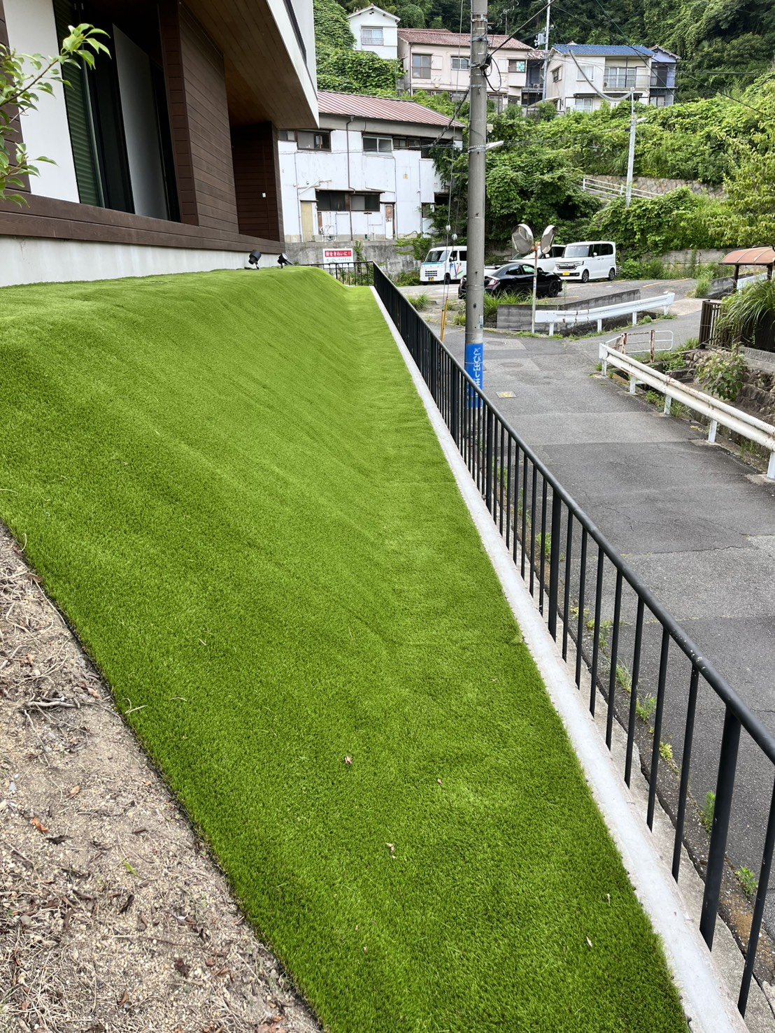 施工後：山の斜面一面に敷き込んだ人工芝の法面