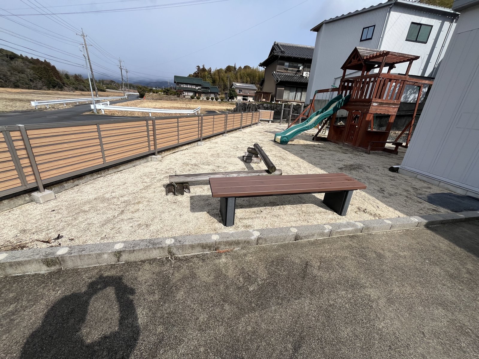 施工前:砂敷きの庭に置かれた木製遊具とベンチ