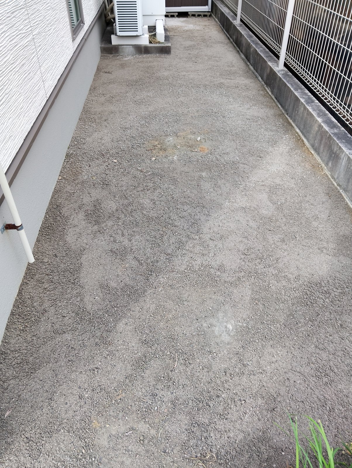施工前：砂利と土がむき出しの建物脇の犬走り