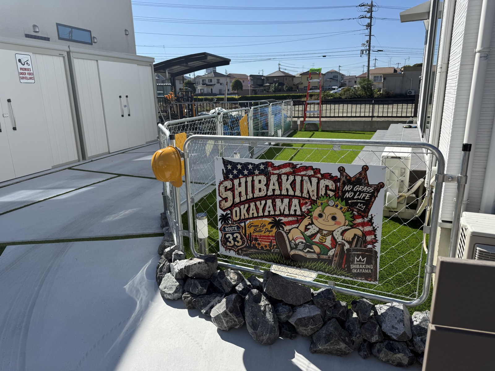 施工後：芝キング岡山の看板を掛けたフェンスの奥に広がる人工芝のお庭